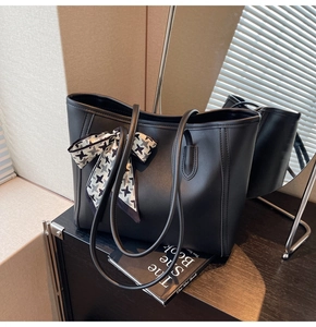 Detail of black faux leather tote bag with a houndstooth scarf bow and long shoulder straps