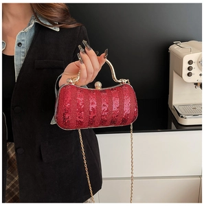 Detail of red sequin evening clutch with gold metal handle and pearl clasp decoration