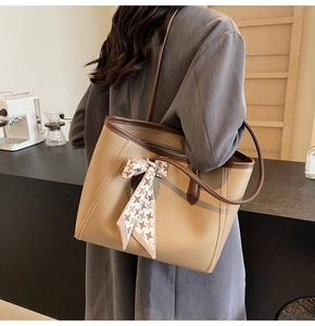 Khaki tote bag with brown handles and houndstooth scarf detail in a cafe setting
