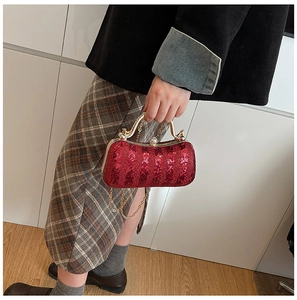 Macro shot of red sequin clutch evening bag featuring golden metal frame and chain strap