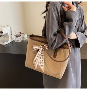 Detail of khaki tote bag with dark brown trim and elegant houndstooth scarf in cafe setting