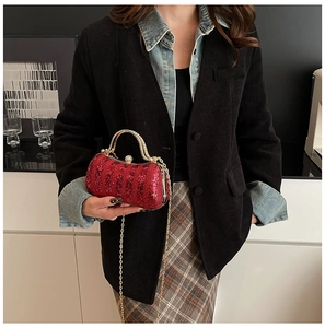 Detail of red sequin evening bag featuring a gold metal handle and luxury chain strap