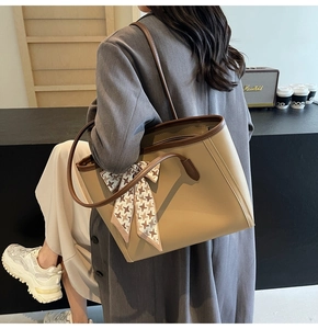 Detail of khaki tote bag with houndstooth scarf and dual straps in an urban office setting