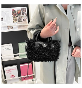 Close-up of black plush faux fur handbag with leather flap and metallic snap button detail