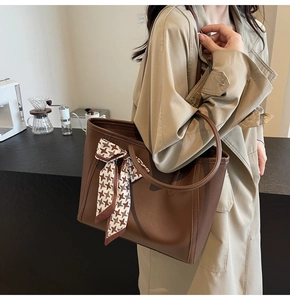 Brown tote bag with houndstooth scarf on a model in a cozy coffee shop setting