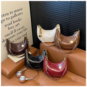 Detail of five glossy crescent hobo bags with metallic chains and crinkled texture