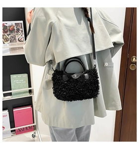 Detailed view of a black plush crossbody bag with faux fur texture and leather flap handle