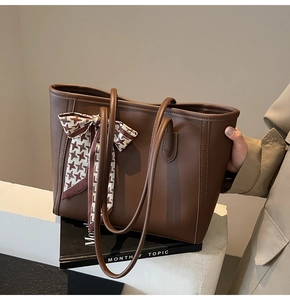 Detail of dark brown leather tote bag featuring a houndstooth silk scarf on handle