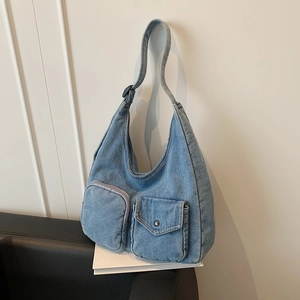 Vintage blue denim hobo bag featuring functional front pockets and a wide shoulder strap