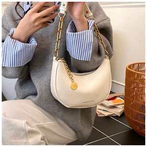 Close-up of white crescent shoulder bag with pleated texture and gold chain strap