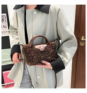 Detailed close-up of dark brown plush faux fur handbag with leather handle and metal buckle
