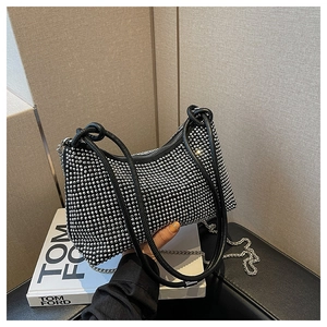 Detailed view of silver rhinestones on black handbag with metal chain strap