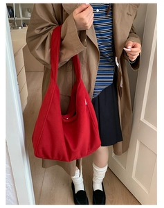 Detail of red large capacity felt tote bag carried by model in khaki trench coat