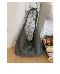 Detailed texture of dark grey wool hobo shoulder bag in a minimalist cozy indoor setting