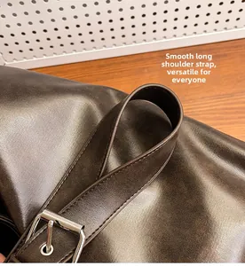 Detail of adjustable coffee brown leather shoulder strap with silver metal buckle and stitching