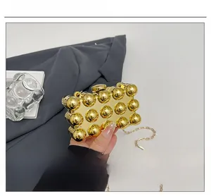 Detail of creative gold spherical box bag with textured mirror surface and chain strap