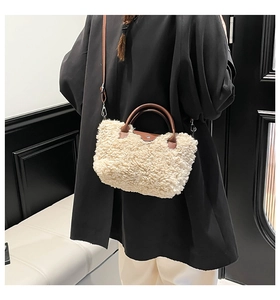 Detail of plush lamb-style crossbody bag with brown leather handle and metal clasp