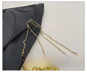 Detail of a golden metal chain strap and spherical relief accents on an acrylic box bag