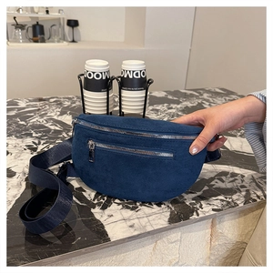 Detail of navy blue suede chest bag featuring silver zippers and wide woven shoulder strap