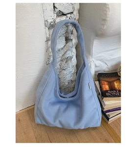 Detail of light blue fuzzy plush handbag showing soft texture and metal magnetic closure