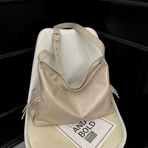 Detail view of beige soft leather tote with wide adjustable strap and side pocket
