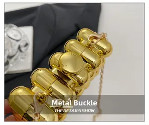 Close-up of high-polish gold hardware clasp and chain on a modern acrylic box clutch