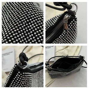 Detailed close-up of a black rhinestone evening bag with silver metal zippers and hardware