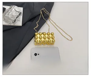 Mini acrylic gold block clutch bag size comparison with a smartphone and chain strap