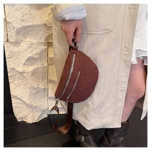 Detail of dark brown suede crescent chest bag with silver zippers and adjustable strap