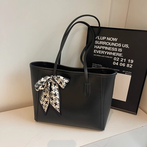 Large black leather tote bag with houndstooth silk scarf on minimalist marble surface