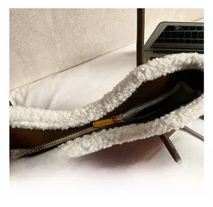 Close-up of golden zipper and white faux fur trim on a brown suede tote bag