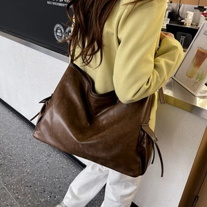 Detail of soft leather shoulder bag in dark brown with retro texture and side drawstring