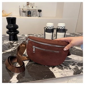 Detail of brown faux suede waist bag with double silver zippers on a marble table