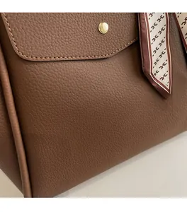 Dettaglio borsa a mano in pelle martellata marrone con chiusura in metallo oro