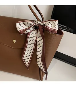 Dettaglio della borsa tote in pelle marrone scuro con foulard decorativo in seta con H