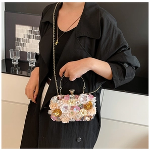 Detailed close-up of 3D sequined flower embroidery and gold metal handle on a luxury clutch