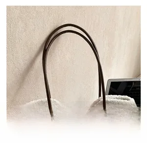 Close-up of coffee suede handbag featuring plush shearling trim and slim leather handles