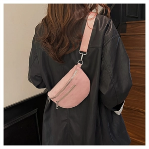 Detail of pink suede chest bag with double zippers and wide fabric shoulder strap