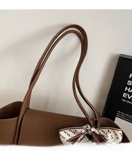 Dettaglio borsa tote in pelle marrone con sciarpa di seta decorativa a motivi in H