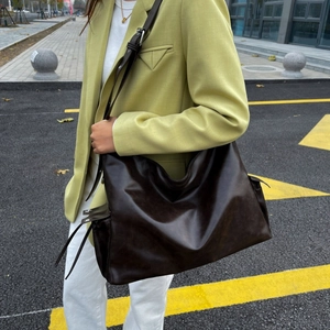 Detail of soft dark brown leather shoulder bag with adjustable buckle strap and drawstring