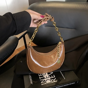 Detail of dark brown hobo bag with glossy wrinkled leather and gold chain strap