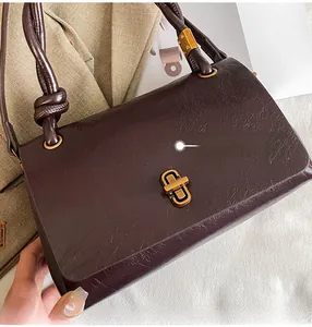 Detail of vintage dark brown leather handbag featuring gold twist lock and corded handle
