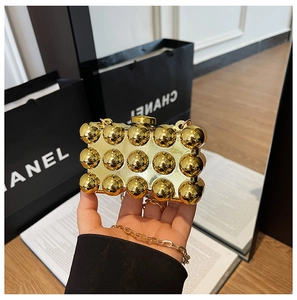 Close-up of gold acrylic box bag with 3D spherical studs and a sleek metal chain