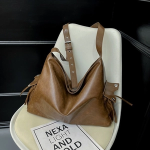 Detail of vintage brown leather hobo bag with silver eyelets and side pocket