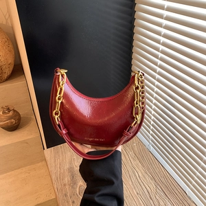 Detail of burgundy leather dumpling bag with chunky gold chain and pleated texture