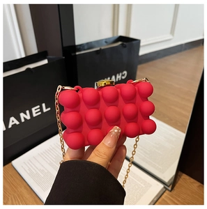 Detail of red bubble texture evening clutch with gold chain strap and metallic clasp