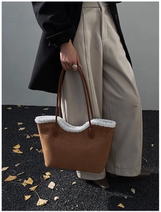 Detail of suede tote bag with white shearling trim styled in an autumn outdoor setting