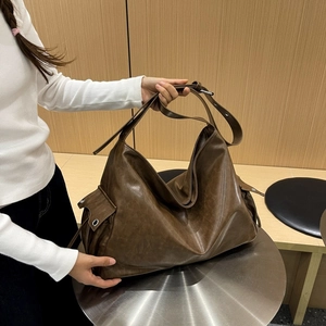 Close-up of matte dark brown leather hobo bag featuring metal eyelets and adjustable strap