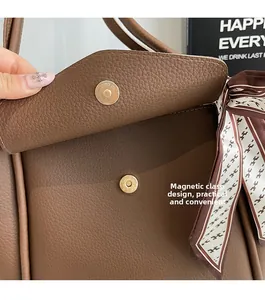 Dettaglio della chiusura magnetica dorata su borsa in pelle marrone a grana fine