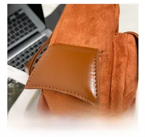 Close-up of side pocket detail on orange suede and brown leather crossbody bag